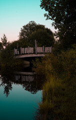 A bridge in the park over a reflective water 