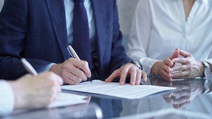 Business people wearing suits signing important documents during a corporate meeting. Win-win concept