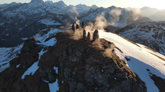 Stone monoliths on a snowy mountain peak with dust devils