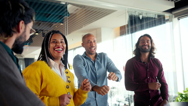Smiling colleagues celebrate together during a playful team building moment in a bright modern office, showing inclusion, motivation, unity and positive energy that strengthens workplace culture.