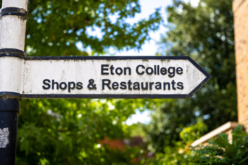 Eton town signpost featuring the crest, photographed against leafy green background