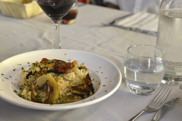 piatto di riso patate e cozze servito con un calice di vino rosso in un ristorante