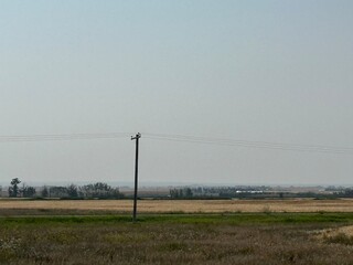 Fototapeta premium power lines on the field, Empty farmland in Alberta captured during early autumn with traces of harvest and panoramic skies