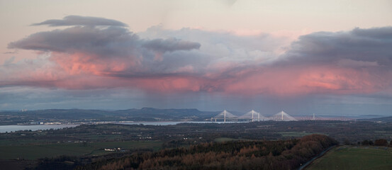 Clouds at sunset over the sea and bridges. Forth Bridges and Queensferry Crossing, Scotland, United Kingdom