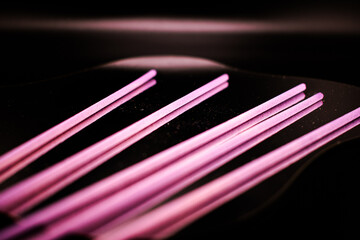 Vibrant lavender incense sticks on a black background, symbolizing relaxation, purification, and the calming energy of aromatherapy and spiritual rituals.