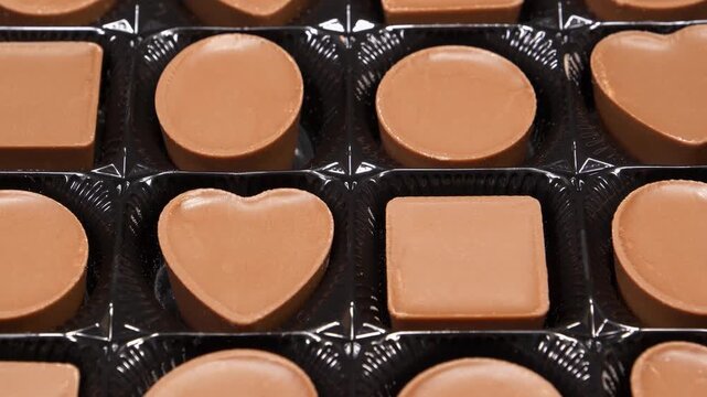 Chocolate candies in packaging. Valentines Day Gift. Candies are square, round and heart-shaped. Delicious chocolate candy with of different forms, including heart-shaped ones