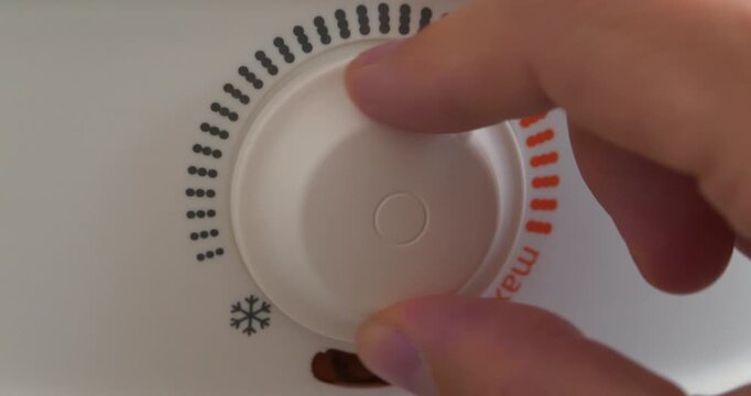 Regulator for heating cold water in boiler. Man turns temperature control on heater. Red light indicator comes on, boiler has turned on to heat water. Boiler heats water from cold water supply system