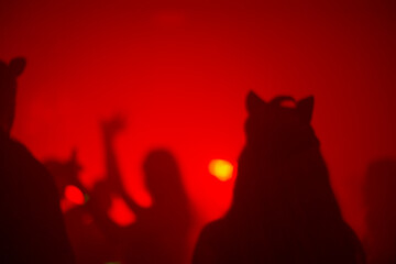 A vibrant party scene featuring silhouettes of people wearing animal ears against a striking red backdrop, creating an energetic and playful atmosphere.