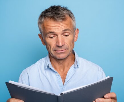 A middle-aged man engrossed in reading a document, his expression focused and attentive against a bright backdrop.