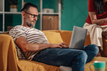 Focused middle aged man working remotely from home on laptop
