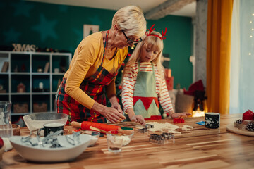 Grandmother and granddaughter making christmas cookies together
