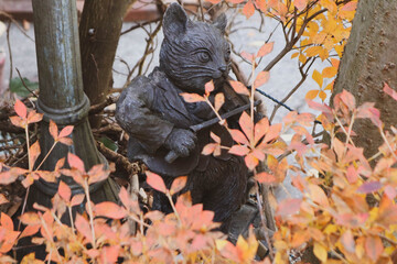 Adorable cat statue playing a violin with autumn leaves.