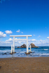 White Torii Gate Standing in the Sea at Futamigaura, Itoshima, Japan Under Blue Sky