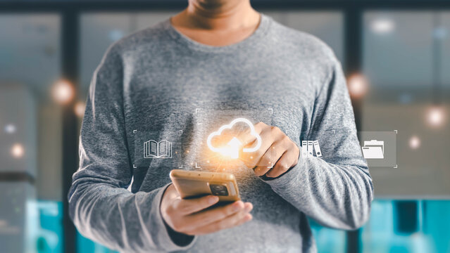A person uses a mobile phone to upload documents and information to an online cloud service for data storage and management in a modern office. - Powered by Adobe