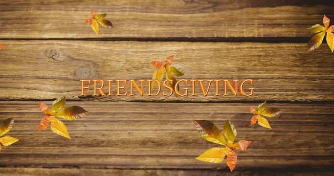 Fototapeta Image of friendsgiving text over autumn leaves on wooden boards