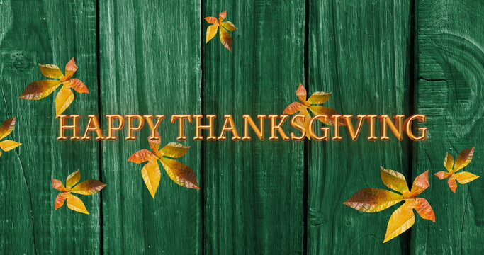 Fototapeta Image of happy thanksgiving text over autumn leaves on green wooden boards