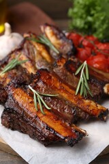 Roasted beef ribs with rosemary and tomatoes on table, closeup