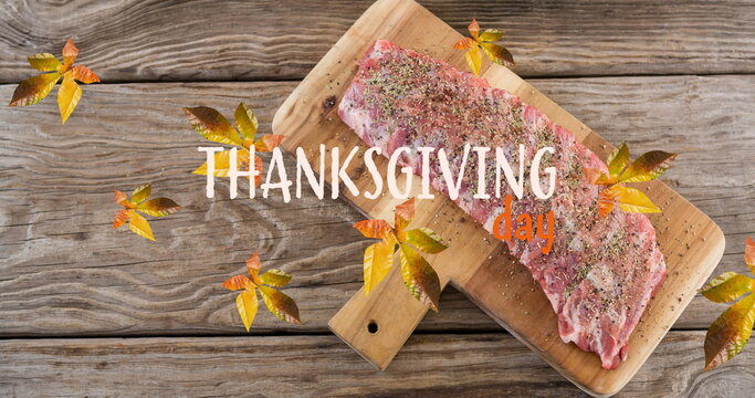 Fototapeta Image of thanksgiving text over autumn leaves and meet on wooden boards