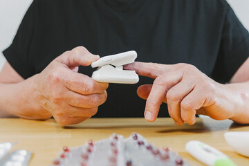 A mature woman measures her pulse with a device.