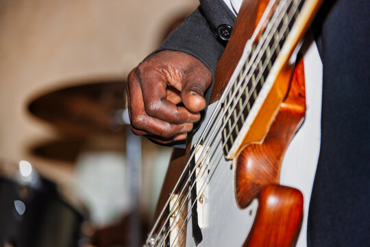 electric guitar, african man playing, close up on the hand and strings, on the stage concert