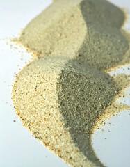 Piles of fine sand and gravel on a white surface