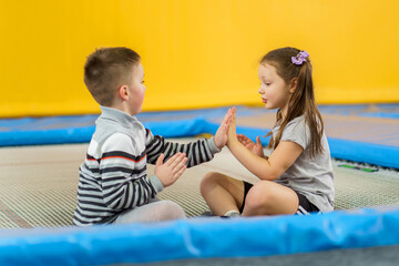 Happy smiling small kids jumping on indoors trampoline in entertainment center