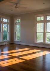 Fototapeta premium Sun-drenched parquet floor illuminates an empty room with large windows, suggesting spaciousness and serenity