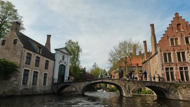 Picturesque canal scene in Bruges, Belgium, featuring a stone bridge, historic Flemish gabled houses