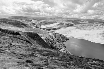 A black and white photo of a mountain range with a lake in the foreground