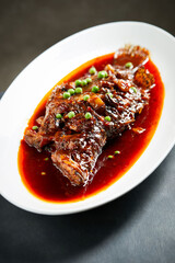 Spicy braised fish on a white plate, top view