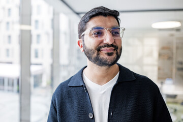 Confident professional man poses gracefully in modern office space, radiating ambition and focus