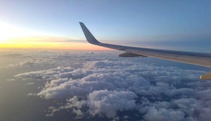 Obraz premium Airplane Wing Above Clouds at Sunrise