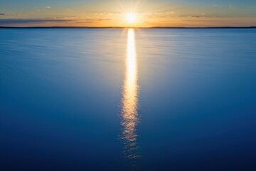 Obraz premium Serene ocean sunset with golden sunbeam reflecting on calm blue water