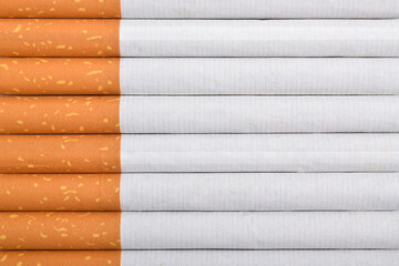 Close up of stacked cigarettes with brown filters and white paper, arranged in rows, isolated on white background.