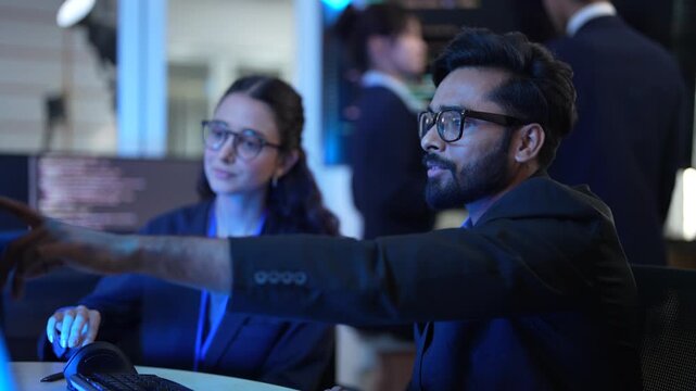 A lead AI engineer discusses a machine learning model's performance with a data scientist. They are analyzing computer simulations and AI algorithm outputs in a tech hub.