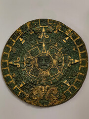 Ancient Aztec calendar stone with golden and green details, featuring intricate carvings and symbolic figures. Cultural artifact representing history, time, and ancient civilization