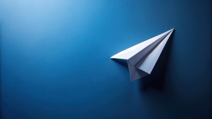 A simple white paper airplane on a deep blue background represents dreams of flight and the pursuit of aspirations.