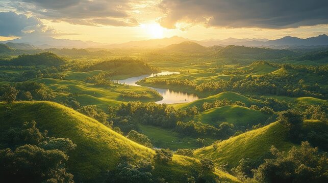 Golden sunlight illuminating rolling green hills surrounding a calm river under a partly cloudy sky with distant mountains on the horizon