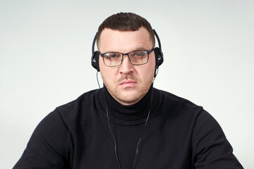 Obraz premium concentrated man in headphones using laptop while sitting over grey background