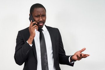 Closeup of angry young african man screaming while talking on smartphone over grey background