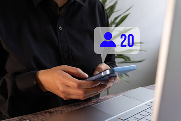 Business person with a computer holding a card and a smartphone with a friend request notification