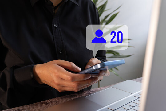 Business person with a computer holding a card and a smartphone with a friend request notification - Powered by Adobe