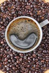 Hot black coffee cup with coffee beans  as background.