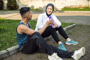 Asian Couple Resting Post Workout and Enjoying a Friendly Conversation Outdoors