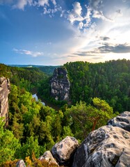 Panoramic view of a valley with a river, rocks, and lush green forests