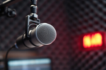 Obraz premium Close-up of professional microphone in recording studio with glowing on-air sign in background, symbolizing podcast or broadcast environment. Ai generative