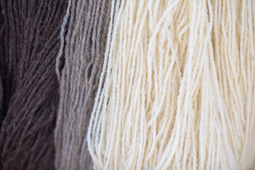 Bundles of natural wool yarn in brown, gray, and cream colors with visible twisted strands and...