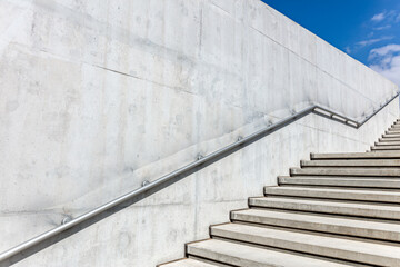 staircase and metal handrail on concrete wall. perspective view on sunny day.