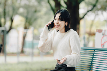 Woman gesturing on phone call in the park. Beautiful woman gesturing talking on the phone outdoors