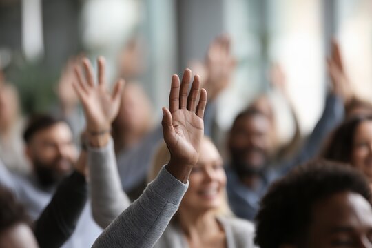 Diverse group raises hands in a business meeting or seminar, concept for active participation, democratic vote and audience engagement